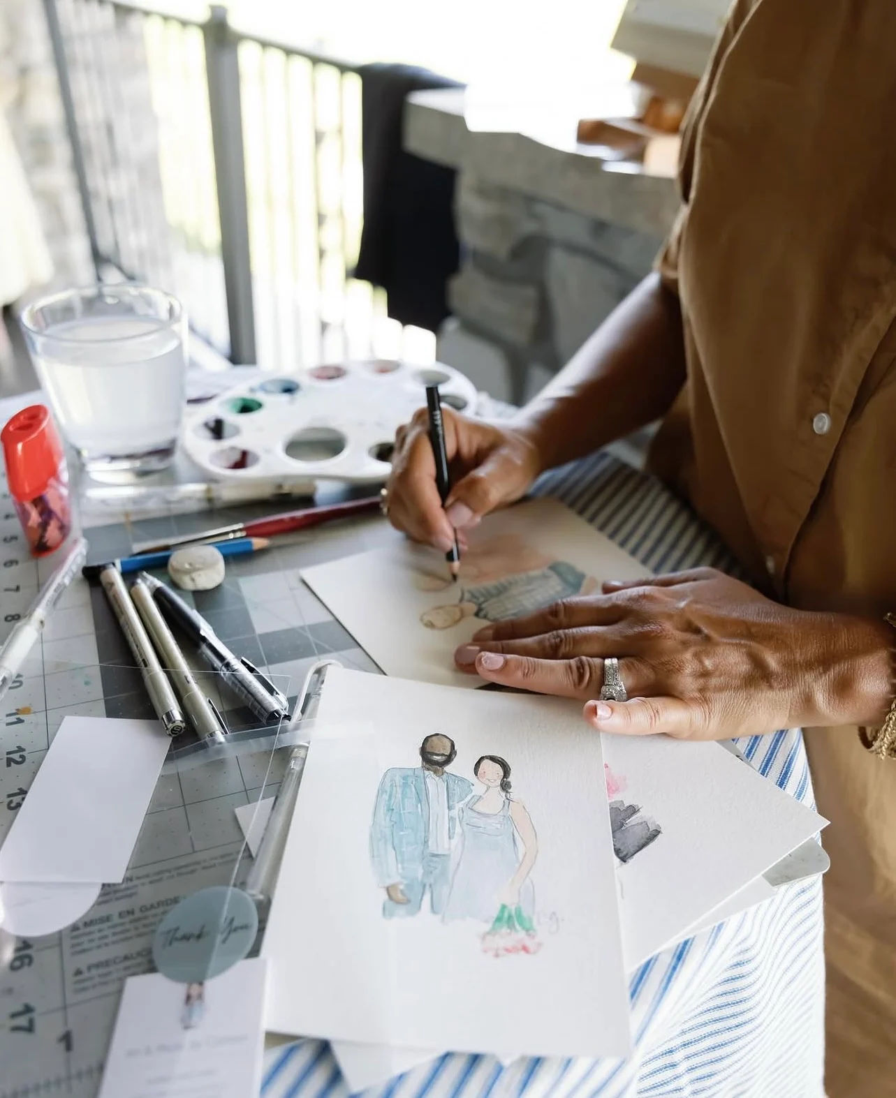 Carmen painting live watercolor guest portraits at her event table