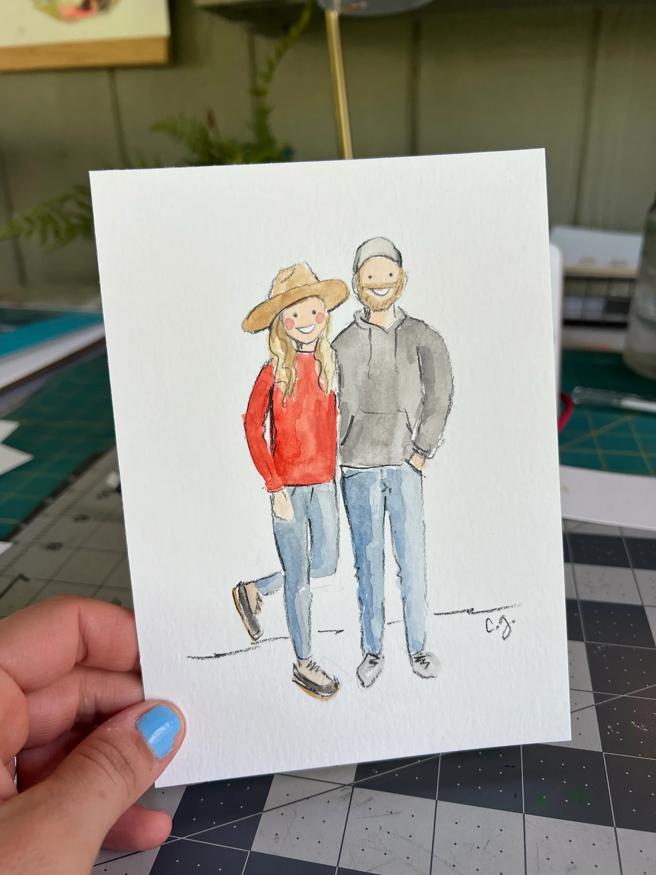 A watercolor couple in a red sweater, wide-brimmed hat, and jeans