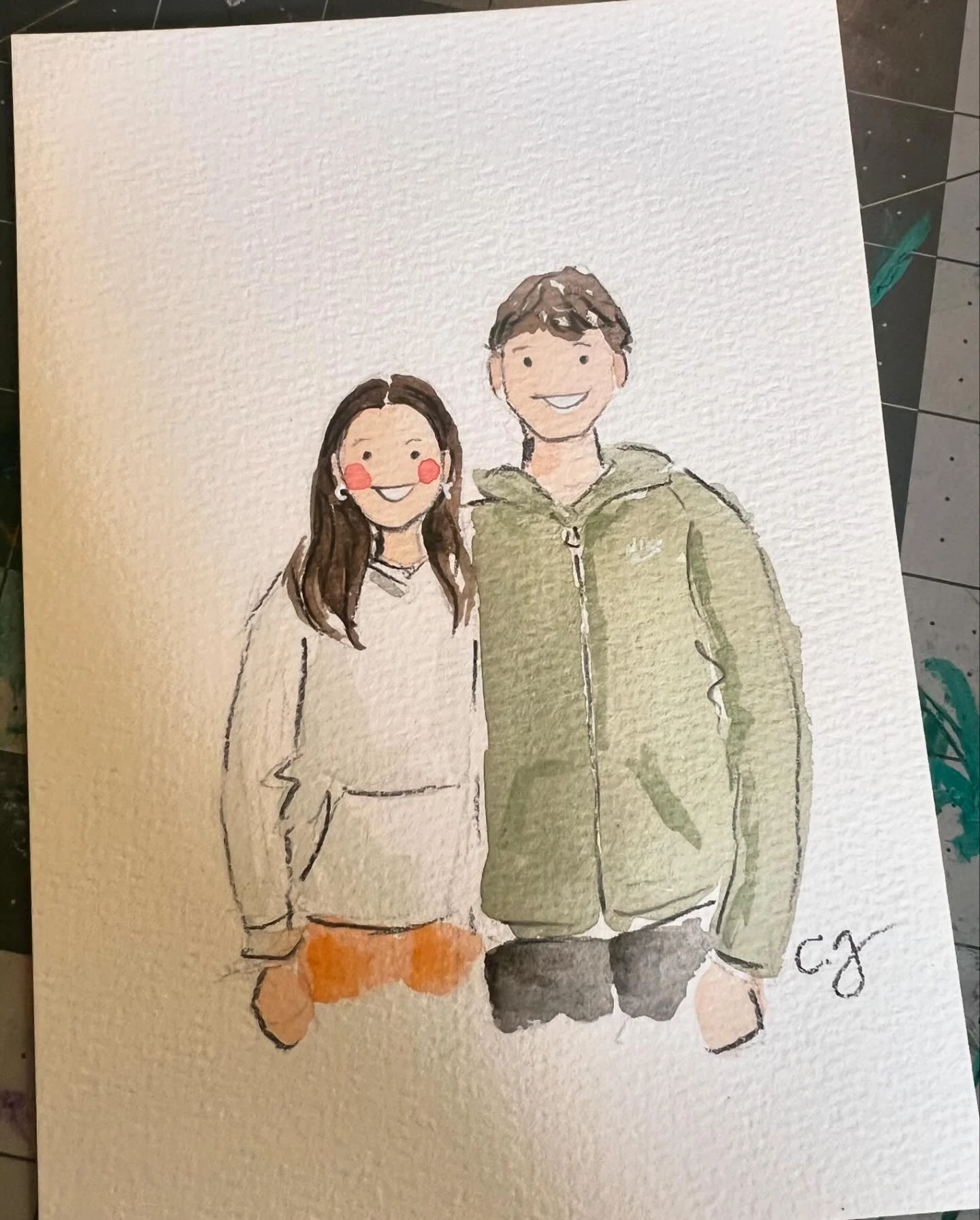 A smiling watercolor couple in a green jacket and gray sweater, signed by Carmen